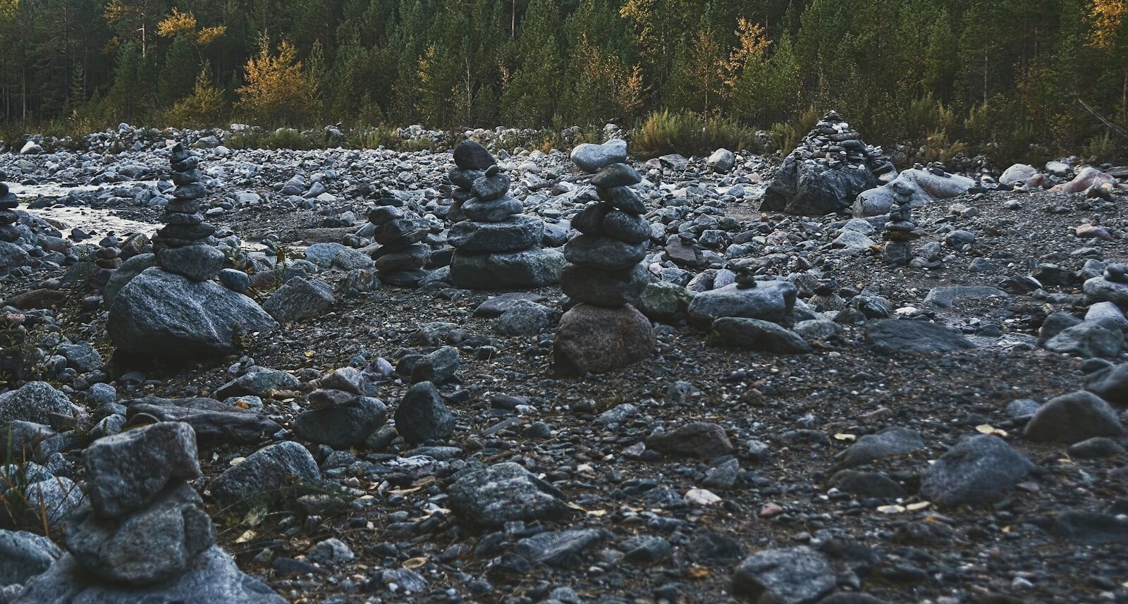 Stacked stones on a rocky riverbed with forest background